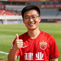一位戴眼镜的中国男性球迷微笑着竖起大拇指，身着红色球迷T恤